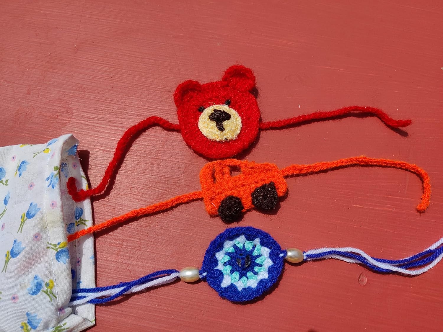 Kids multicolor evil eye, car and teddy rakhi set of 3 crochet rakhi bhaiya bhabhi rakhi gift set for rakhsha bandhan combo set with packed in fabric pouch with roli kumkum and chawal. Color may vary - Image 3